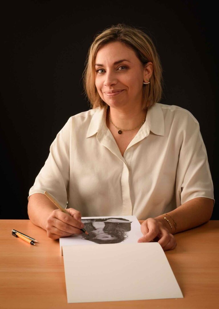 femme illustratrice portraitiste assise a son bureau en train de dessiner
